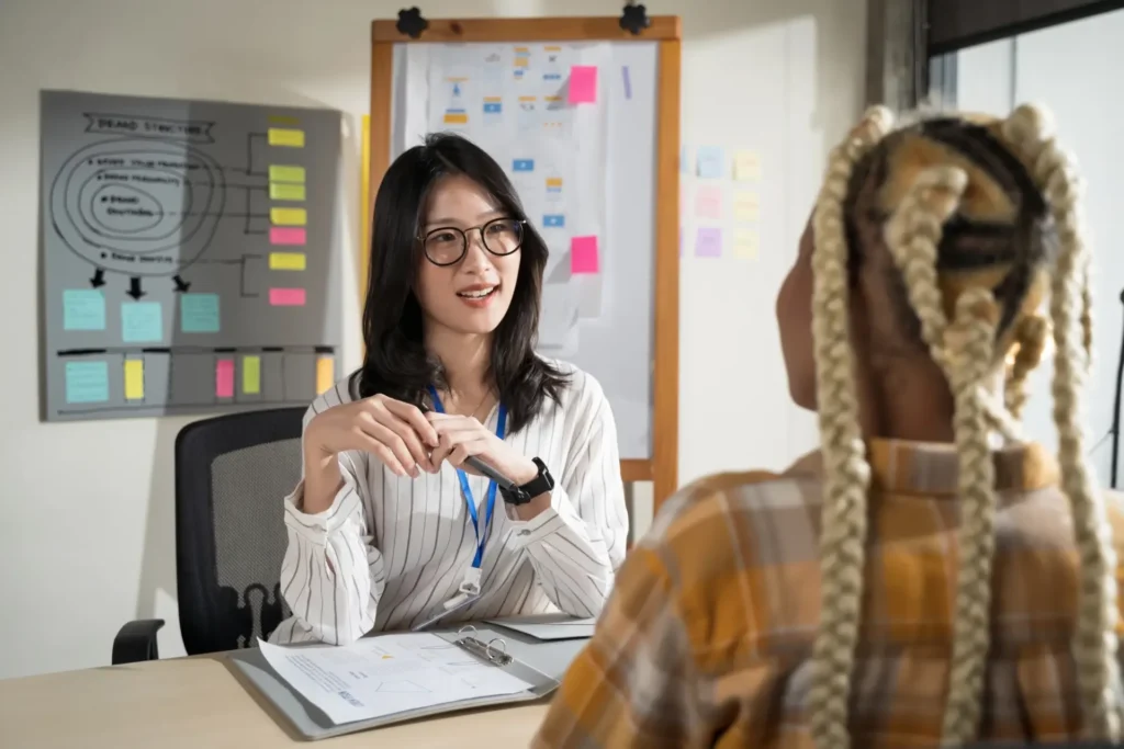 Eine Frau mit Brille führt ein Vorstellungsgespräch mit einer anderen Frau in einem modernen Büro.