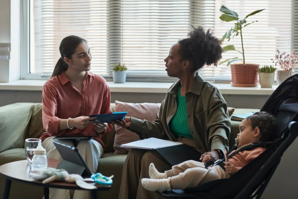 Zwei Frauen unterhalten sich, während ein Baby in einem Kinderwagen schläft.